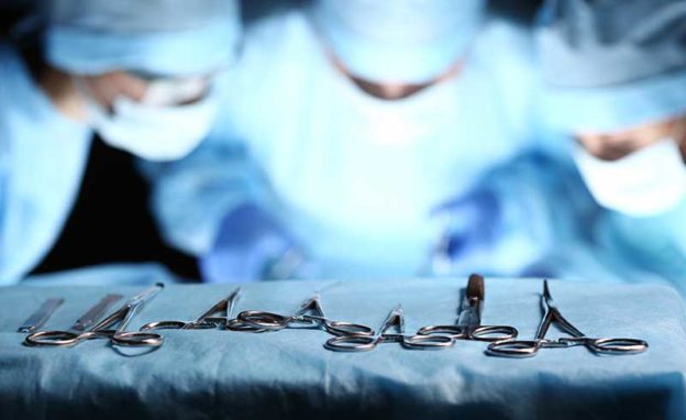 Three surgeons leaning over with tools in the front