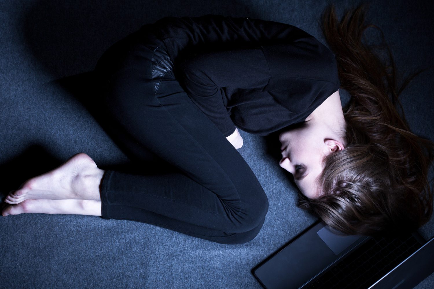 Women curled up on the floor thinking about addiction and Drug Detox