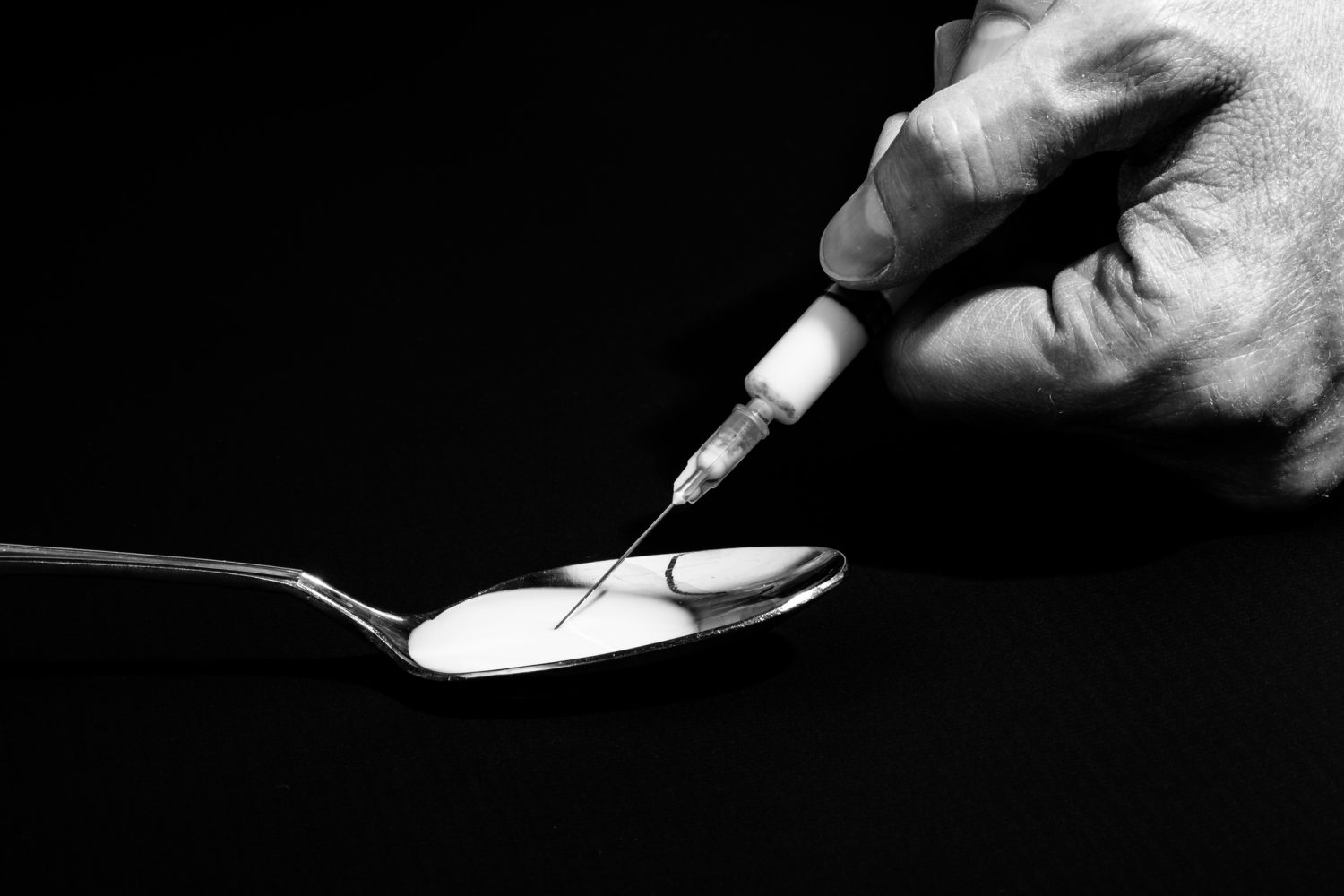 Rapid detox for heroin addiction; hand using syringe over spoon of heroin